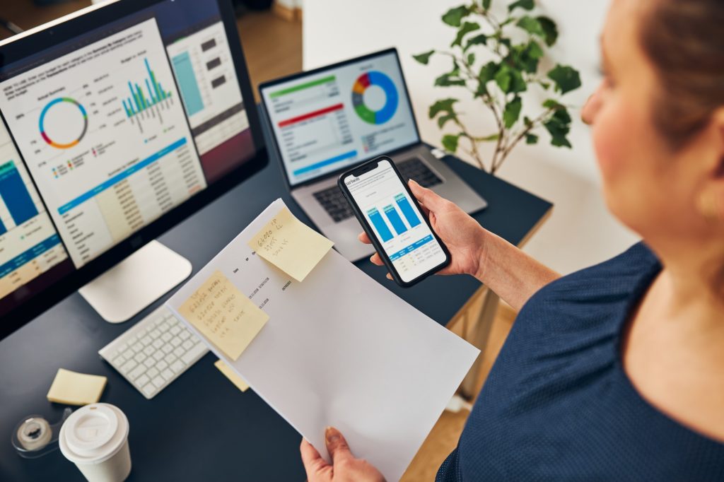 Businesswoman working with financial data on charts and tables on smartphone and computer